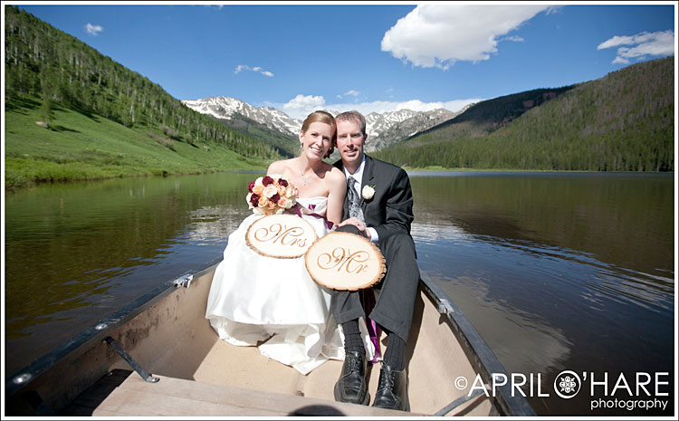 An outdoorsy Colorado couple sit on a canoe on their wedding day in the mountains