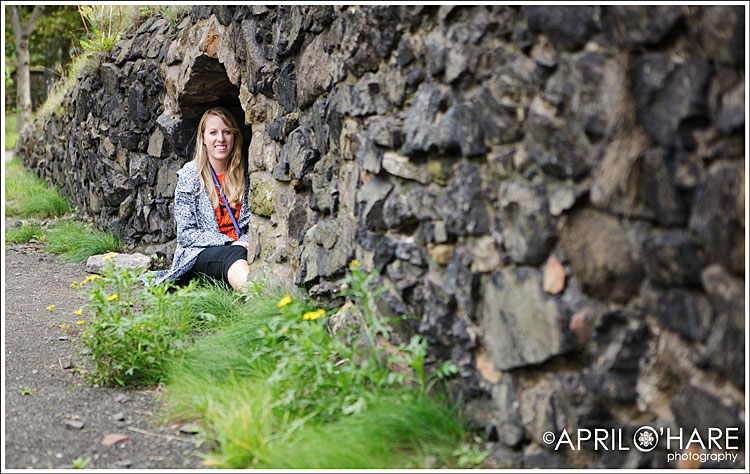 Blonde girl sits by the low rock wall on the hike up to Edinburgh Castle