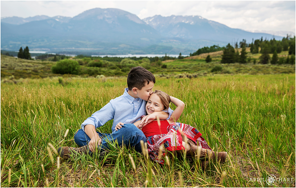 Sweet big brother gives his little sister a kiss on her head during family photos in Colorado