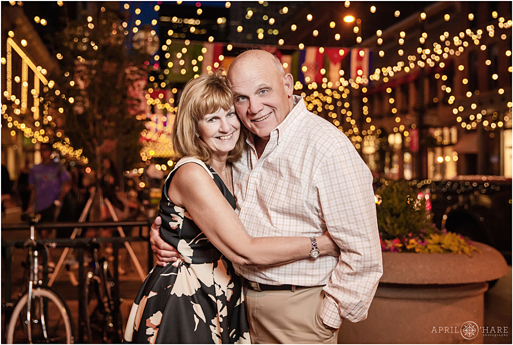 Happy couple pose for a photo in front of the string lights at Larimer Square