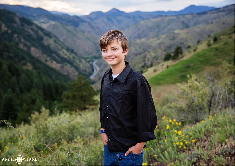 A cute high school freshman boy poses for a portrait with mountain backdrop at Windy Saddle Park on Lookout Mountain in Golden Colorado