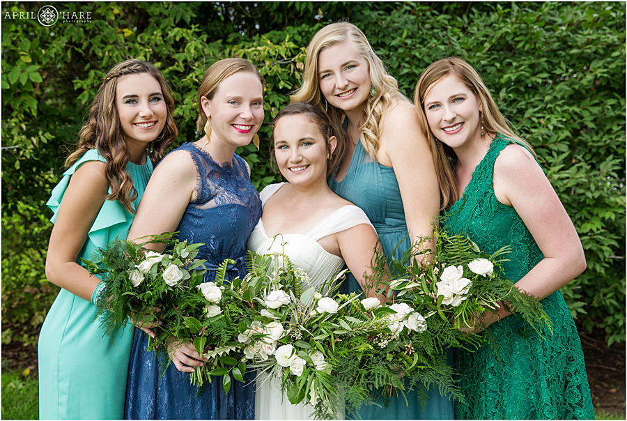 Bridesmaids wearing shades of blue and green at a bohemian wedding at Rustic Colorado venue Chatfield Farms