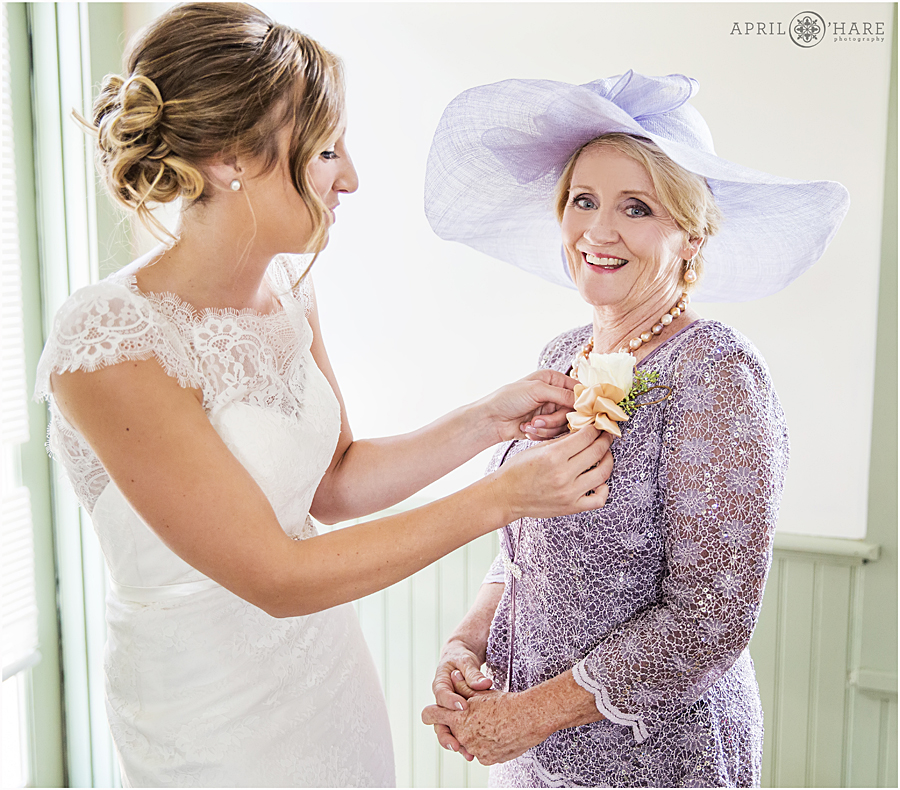 Bride helps her mother in law with her corsage on her Deer Creek Stables Wedding Day at Chatfield Farms
