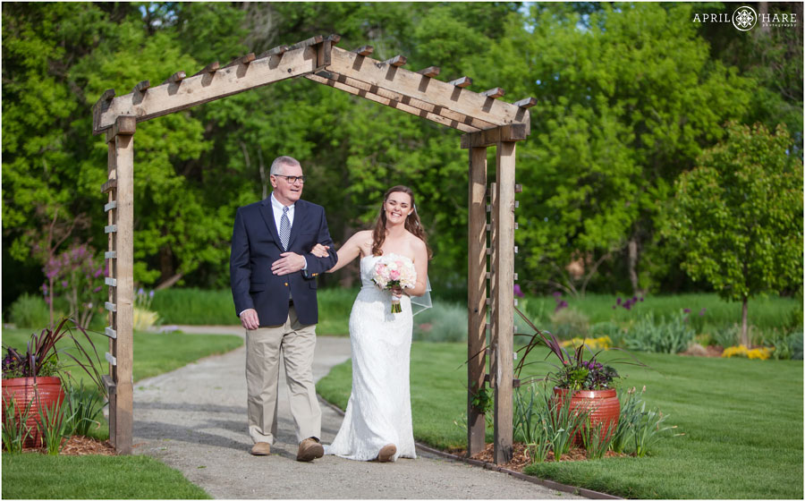 Bride laughs as her dad walks her down the aisle at her Denver Garden Wedding at Chatfield Farms