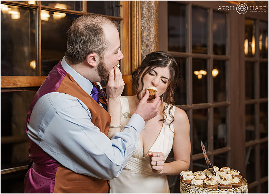 Fun couple at their Colorado Summer Camp Wedding stuffing cupcakes into their mouths