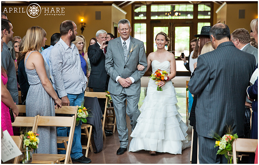 Bride and Dad walk down the aisle at indoor Vail wedding ceremony in Colorado