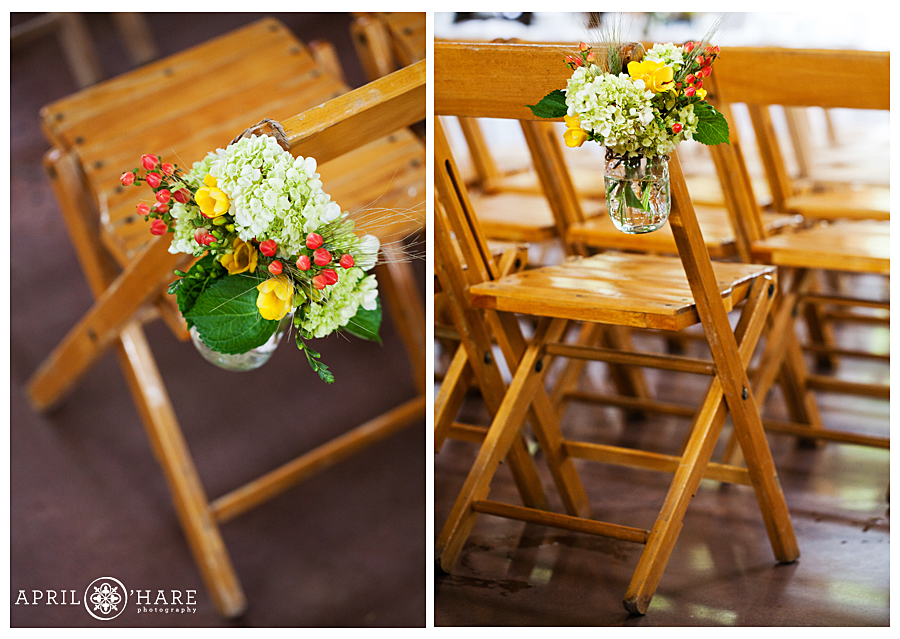 Beautiful orange, red, and yellow floral decor for wood folding chairs at indoor Vail wedding in Colorado