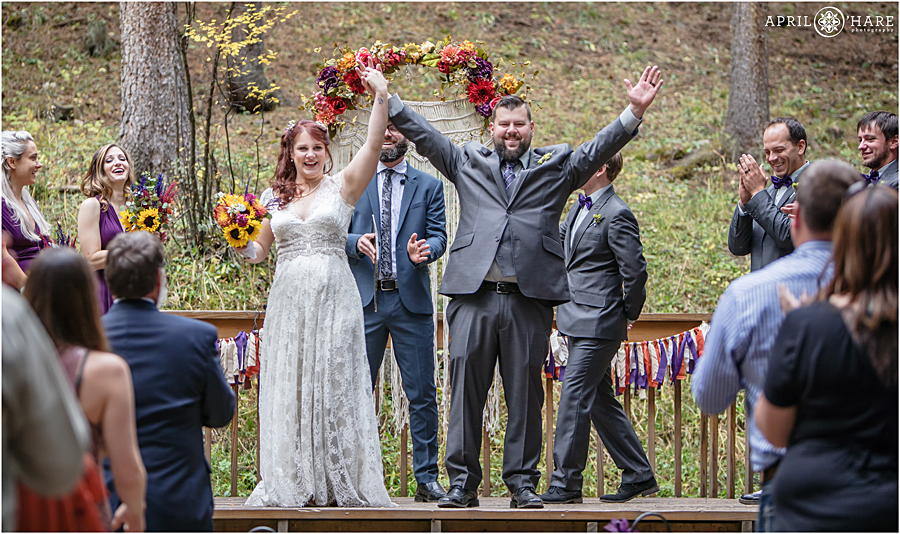 Beautiful Colorado Boho Wedding with macrame arch with fall color florals in a forest setting