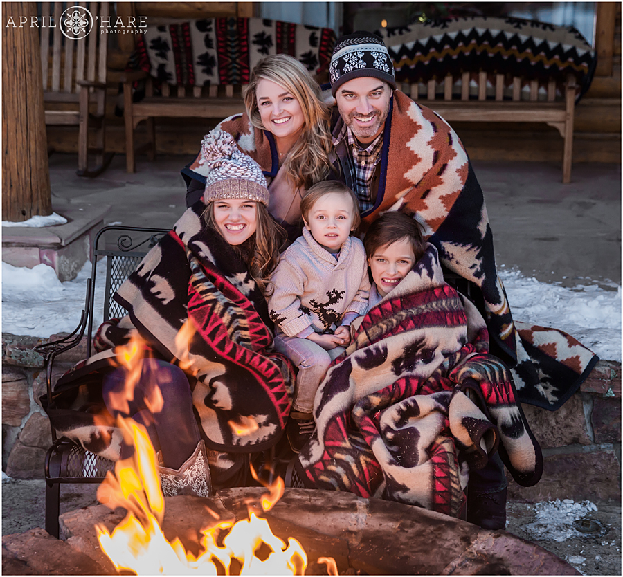 Cute cuddly family photo next to fire pit at C Lazy U Ranch in Grand County, Colorado during Christmas holidays