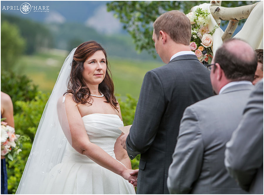 Bride looks at her groom at outdoor ceremony by a Crested Butte wedding photographer