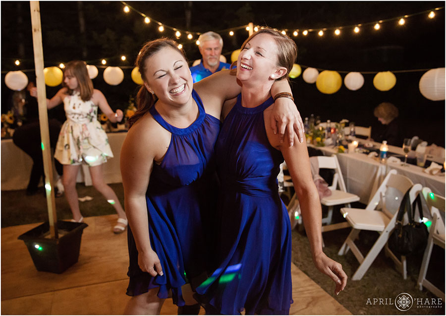 Bridesmaids in bright blue dresses having fun at their friend's Backyard Lesbian Wedding
