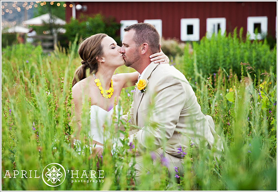 Couple kiss in the gardens at a pretty yellow colored wedding in CO