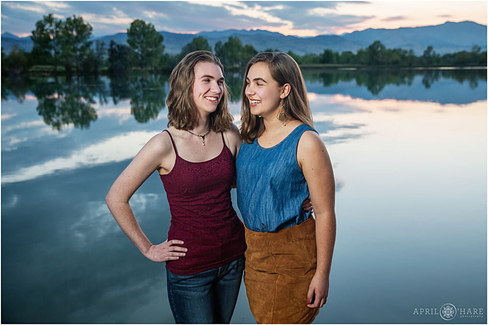Teenage sisters pose for a photo together with a sunset mountain lake backdrop at Coot Lake in Longmont Colorado