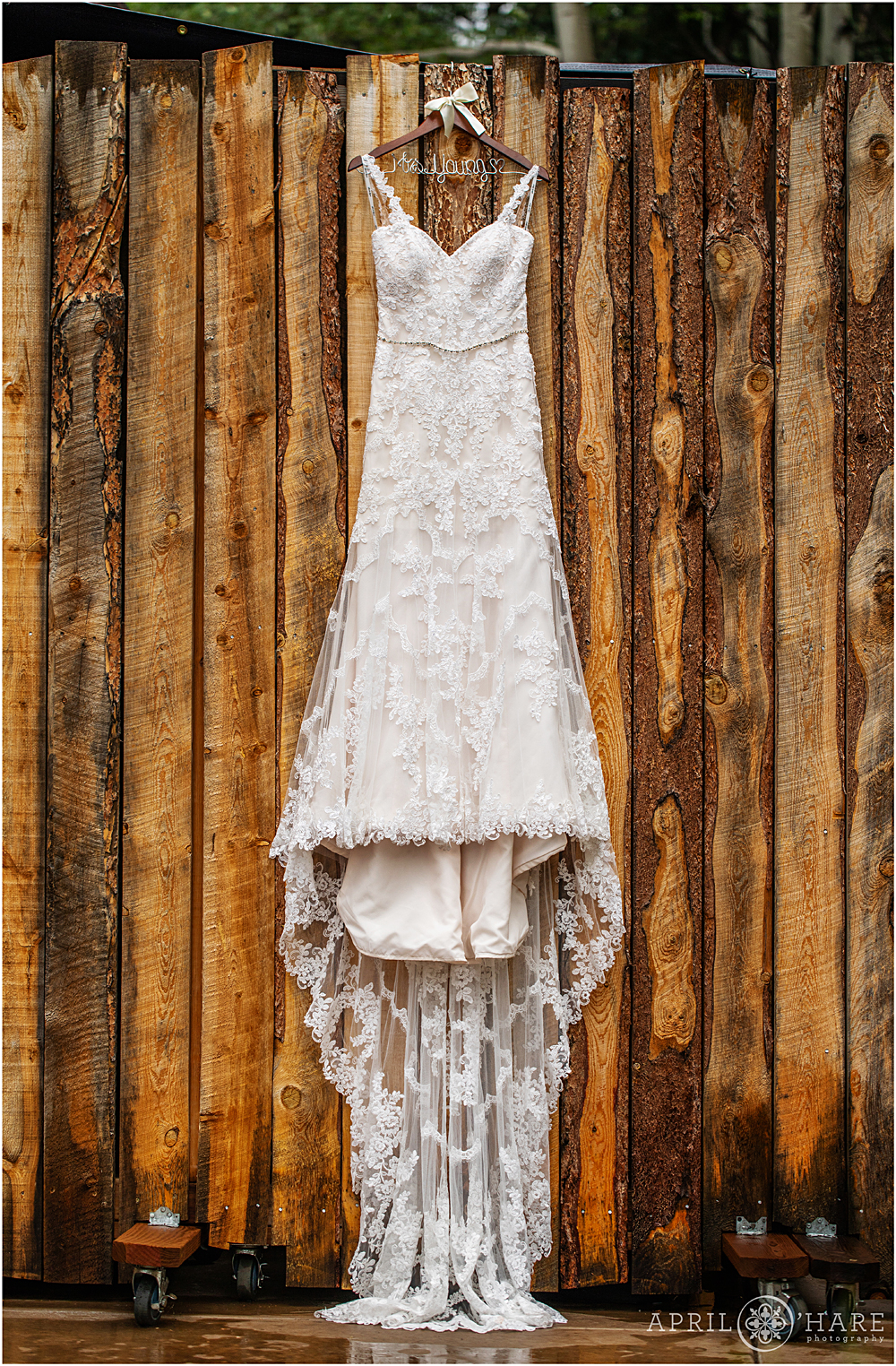 Pretty Lace Wedding Dress Hangs on Wood Wall at Blackstone Rivers Ranch in Idaho Springs