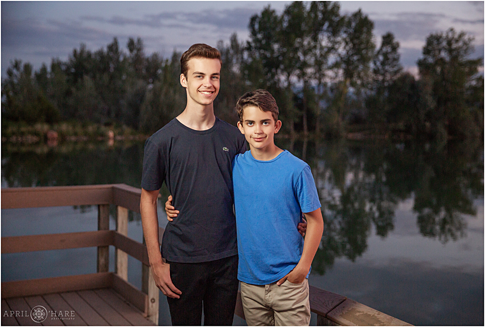 Two teenage brothers pose for a photo together on the dock at Coot Lake  at Sunset in Boulder CO