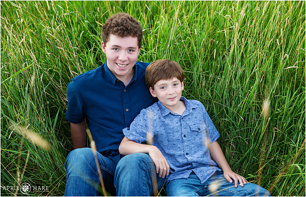 Two brothers hang in the field of tall green mountain grass in Colorado