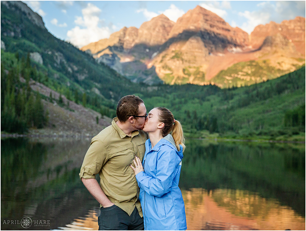 Recently engaged couple kiss in front of Maroon Bells in Aspen