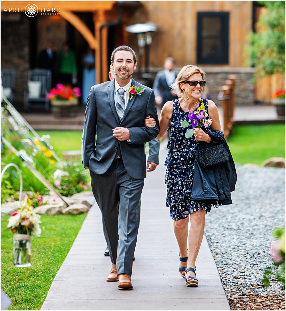Groom walks down the aisle with his mom at Blackstone Rivers Ranch