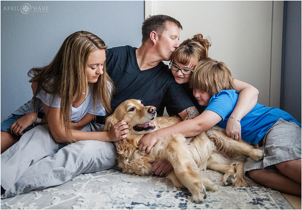 A sweet photo of a family cuddling with their dog at home in Colorado