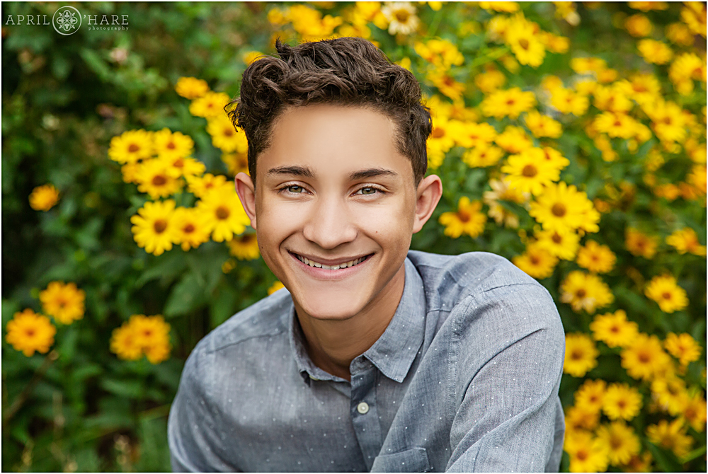 Senior portrait of a boy in a garden along Pearl Street Mall with yellow flower backdrop