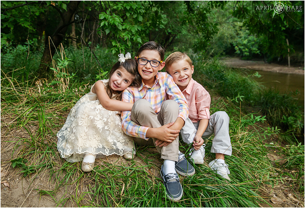 Three Siblings pose for a portrait next to Cherry Creek in Denver