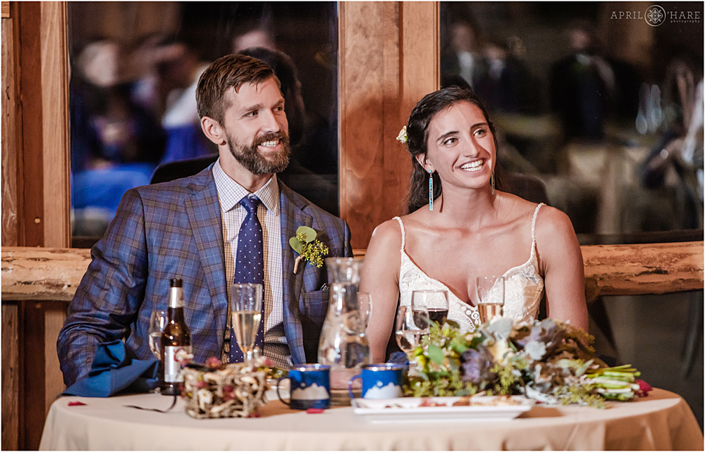 Bride and groom smile during speeches and toasts at Wedgewood Weddings Mountain View Ranch in CO