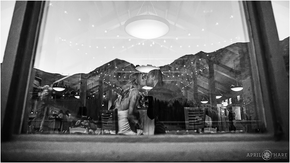 Artistic B&W photo of the bride and groom at their reception with mountain reflection in window
