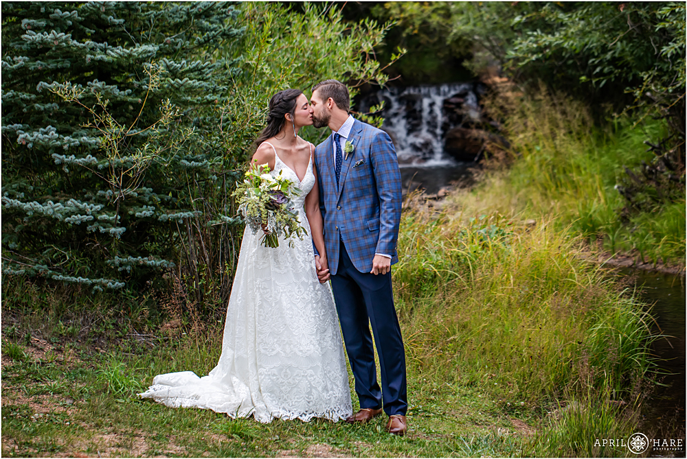 Sweet romantic portrait with small waterfall backdrop on a Romantic Rainy Wedding day in Colorado