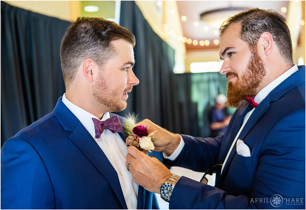 Groom gets help with his boutonniere from brother 