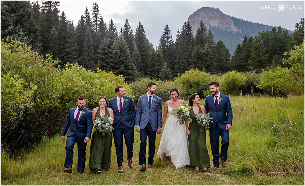 Wedding party walks together in a pretty mountain meadow at Wedgewood Weddings Mountain View Ranch during summer