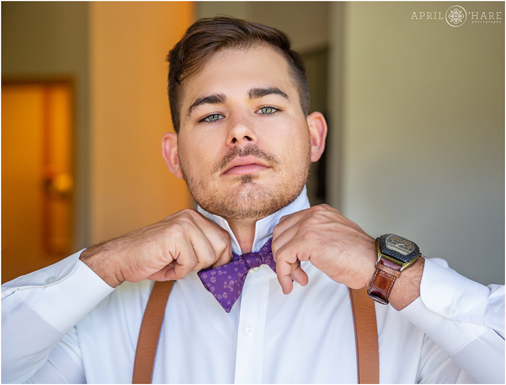 Close up of groom putting his bowtie on at his Colorado mountain wedding in Keystone Colorado
