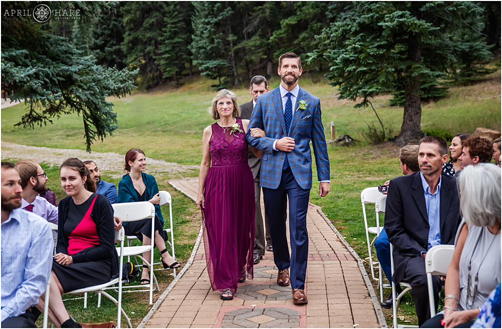 Groom and his mom walk down the aisle at a stormy Colorado mountain wedding at Wedgewood Weddings Mountain View Ranch
