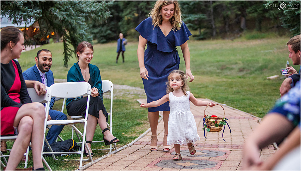 Excited flower girl makes her way down the aisle on a stormy summer wedding day in Colorado