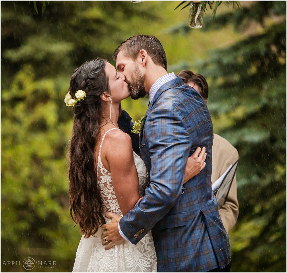 Romantic Rainy Wedding kiss at outdoor ceremony as thunderstorm pours down on the couple