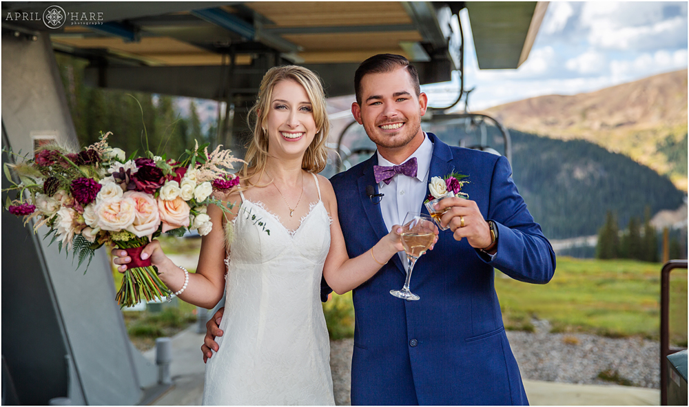 A happy bride and groom celebrate their wedding by riding the chairlift at Arapahoe Basin Ski Resort in Colorado