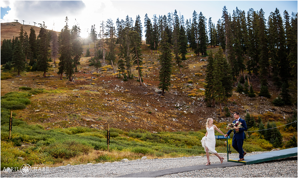Bride and groom walk hand in hand back to their party after chairlift ride at A-Basin