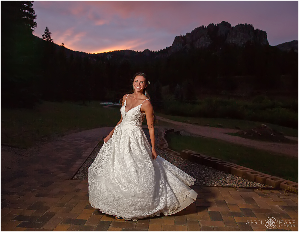 Bride twirls in her dress with pretty purple sunset at Wedgewood Weddings Mountain View Ranch in CO