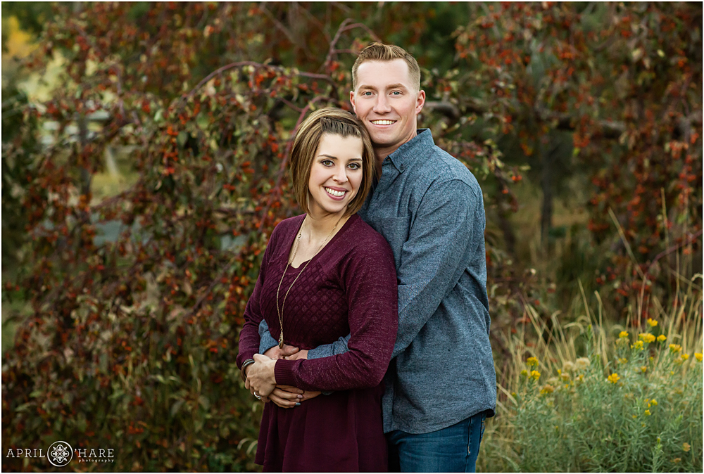 Couple photos in front of a fall red berry tree in Golden CO at the Clear Creek History park