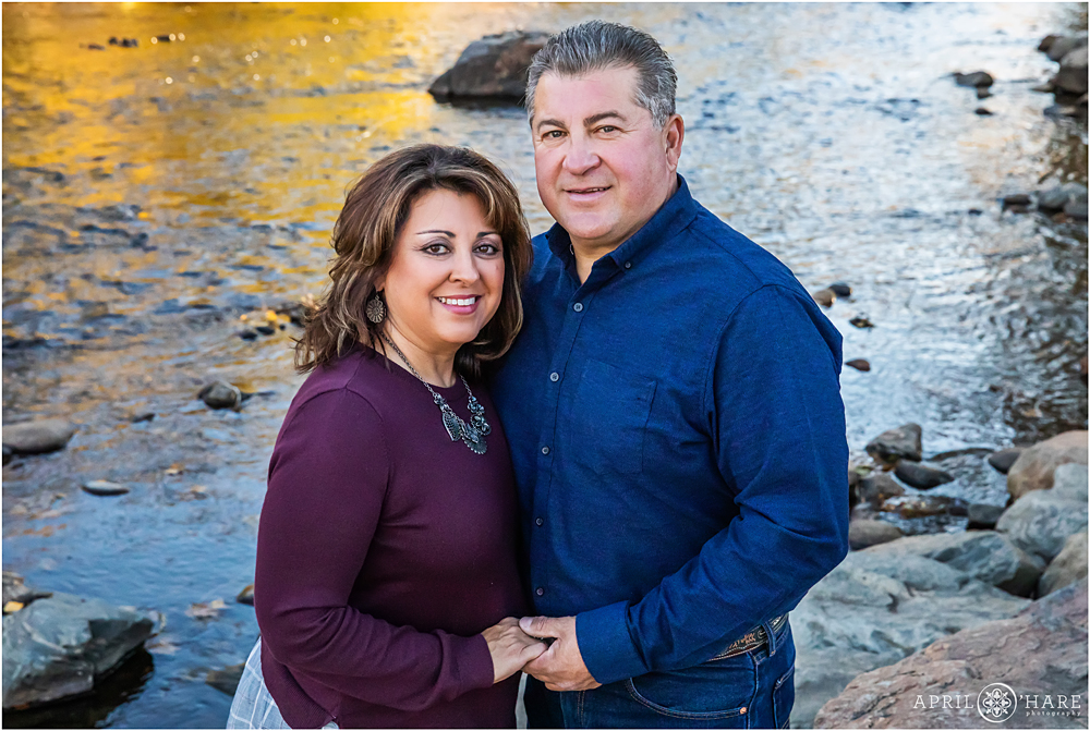 Mom and Dad of an extended family pose for a portrait in front of Clear Creek in Golden
