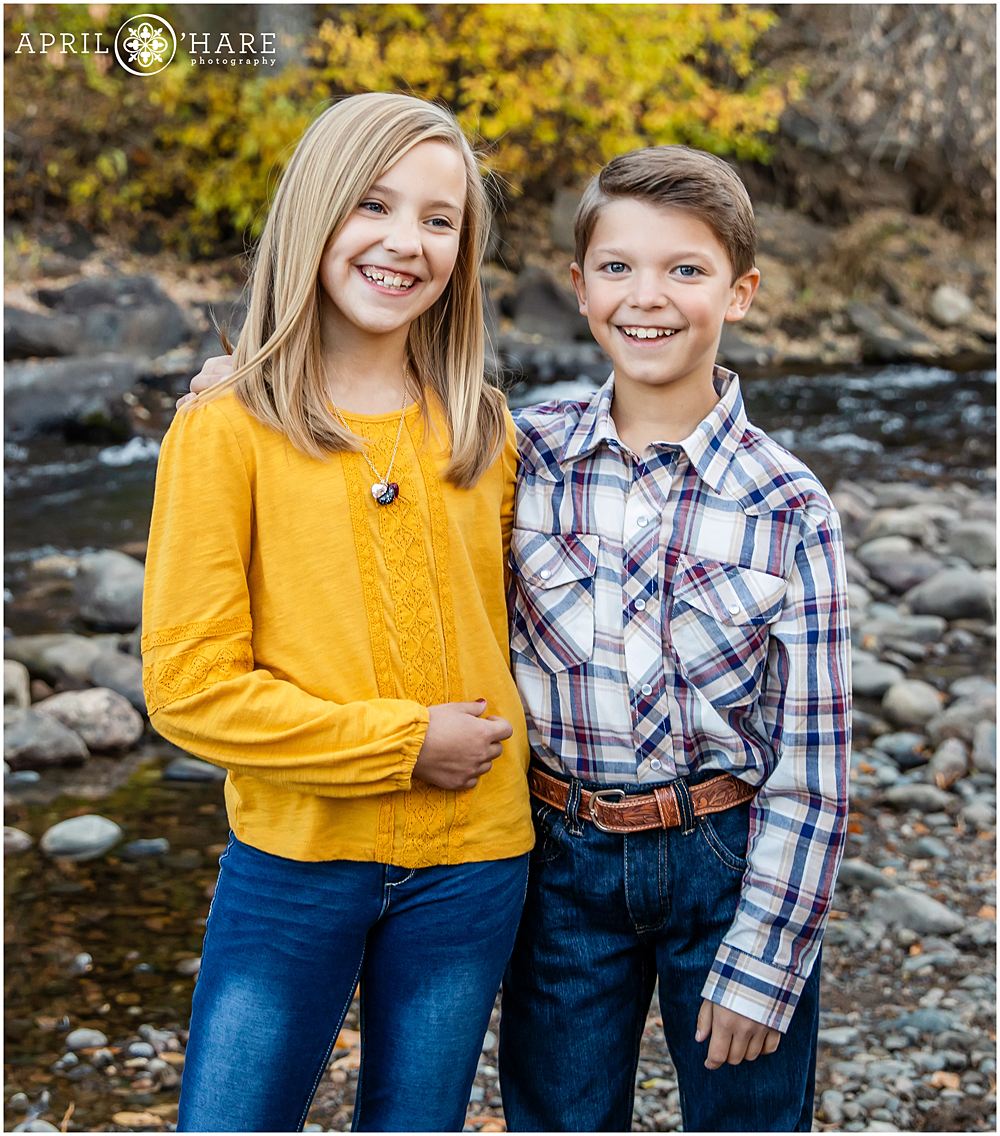 Brother and sister laugh together at their family photos at Clear Creek in Golden Colorado