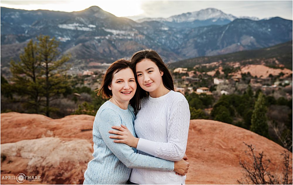 Mother and daughter together on red rocks with blue mountain backdrop at Garden of the Gods in Colorado Springs