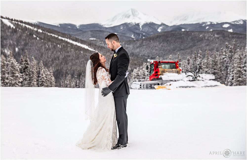 Cute wedding photo with snow groomer in the backdrop at Keystone Resort