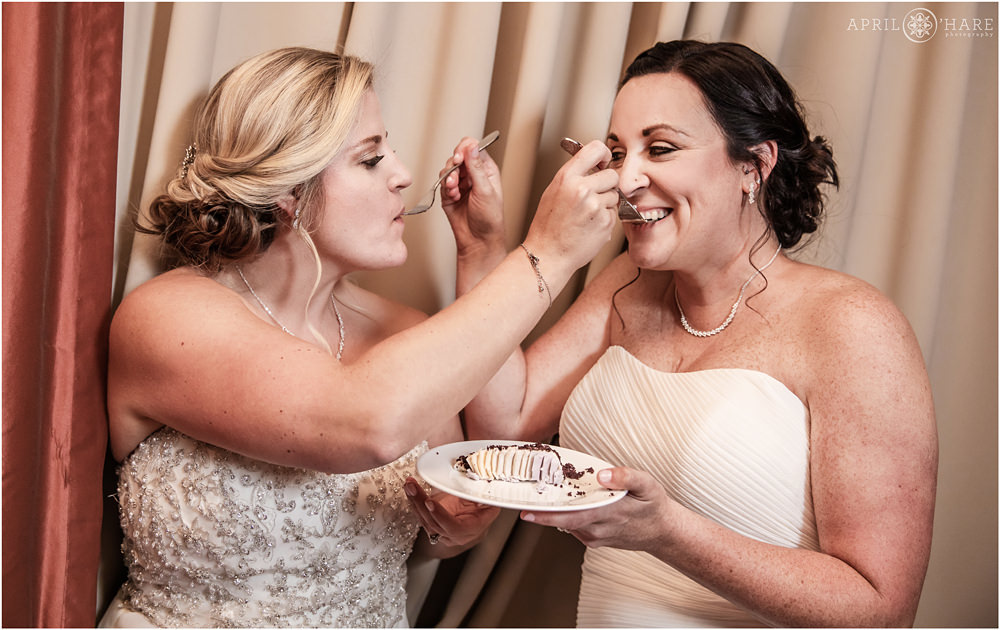 Brides feed each other cake at their Golden Hotel Wedding in Colorado