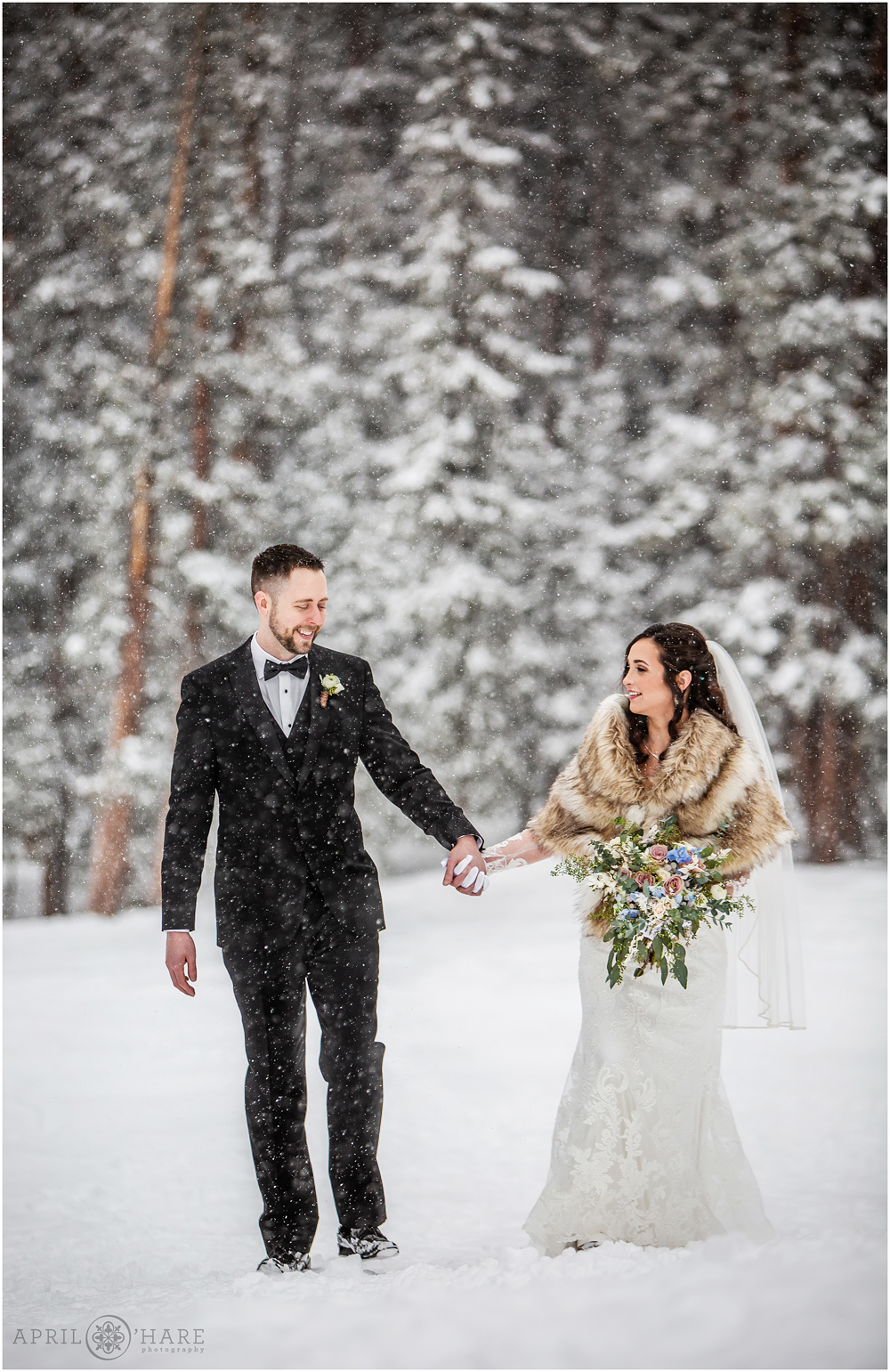 Couple walks hand in hand through the snow at their Winter wedding at Keystone Resort in Colorado