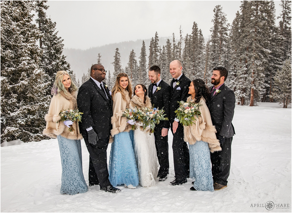 Wedding party laughing during outdoor formal portraits at a snowy destination wedding in Keystone Colorado