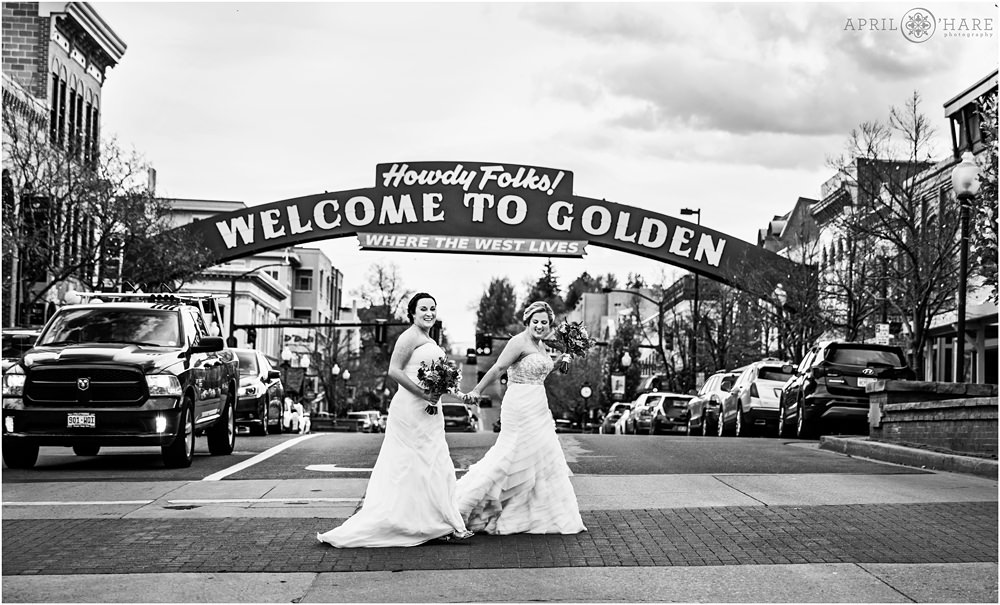 Cute Lesbian Couple crosses the street under the Welcome to Golden Sign