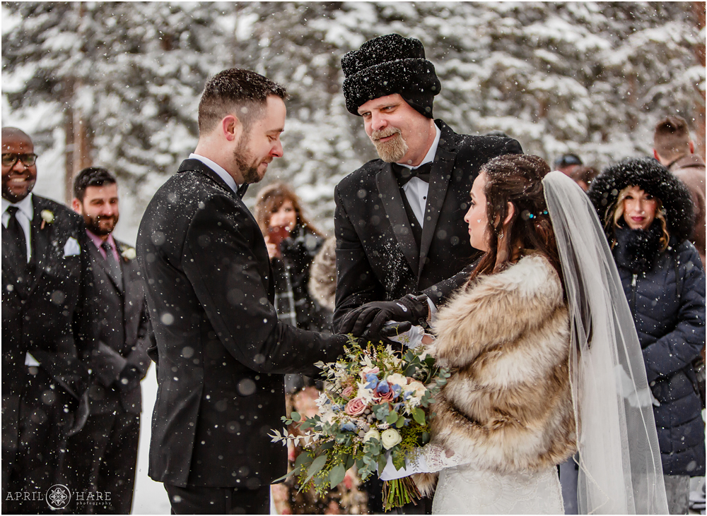 Father of the bride gives his daughter away at an outdoor snowy winter wedding at Keystone Resort in CO