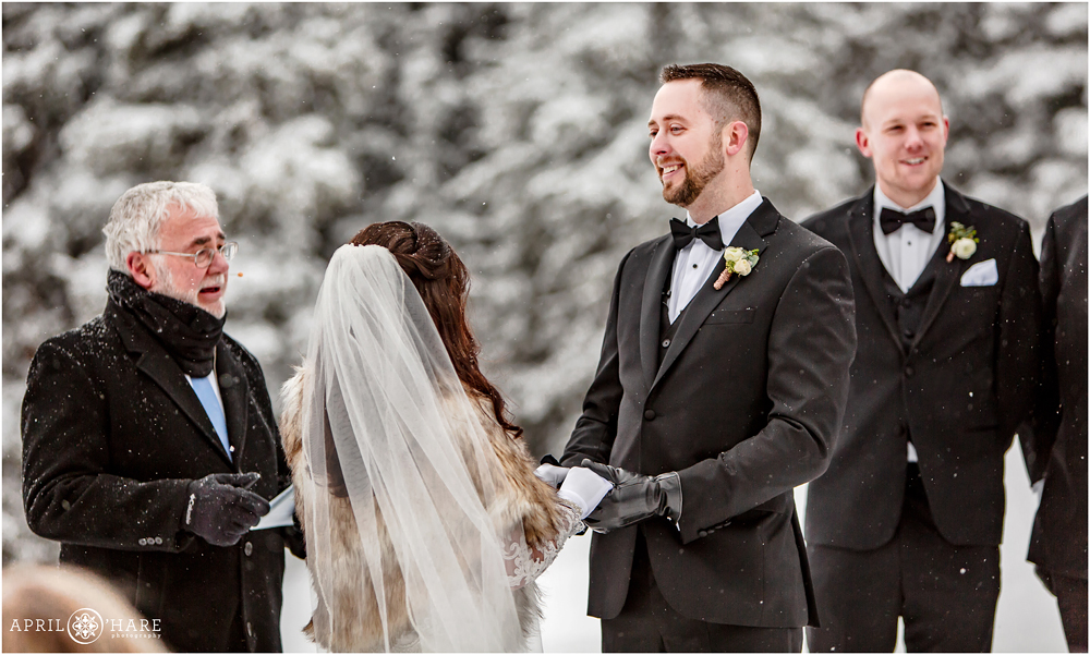 Groom looks at his bride during outdoor winter wedding ceremony at Keystone Resort in Colorado