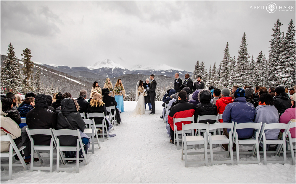 Wide angle view of an outdoor winter wedding ceremony during a snowstorm at Anticipation Run in Keystone