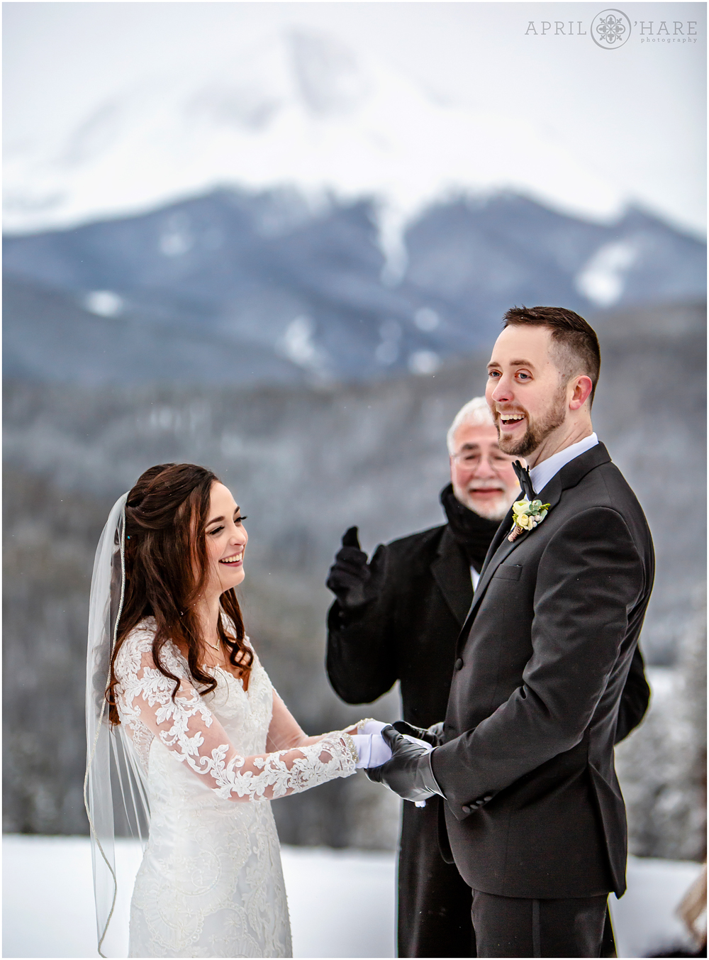 Bride in long sleeved lace dress and her groom at their outdoor winter wedding in Keystone